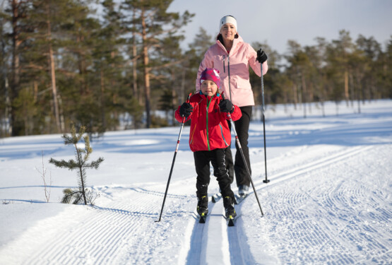 Flicka åker längdskidor tillsammans med mamma.
